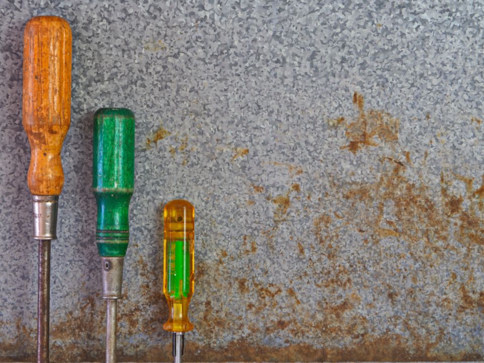 Three screwdrivers standing against a worn stone wall